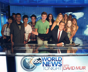 Image of David Muir at his anchor's desk surrounded by FastForward reporters