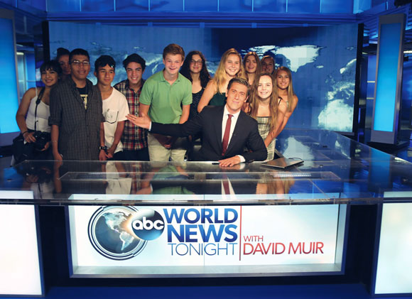 Image of David Muir at his anchor's desk surrounded by FastForward reporters